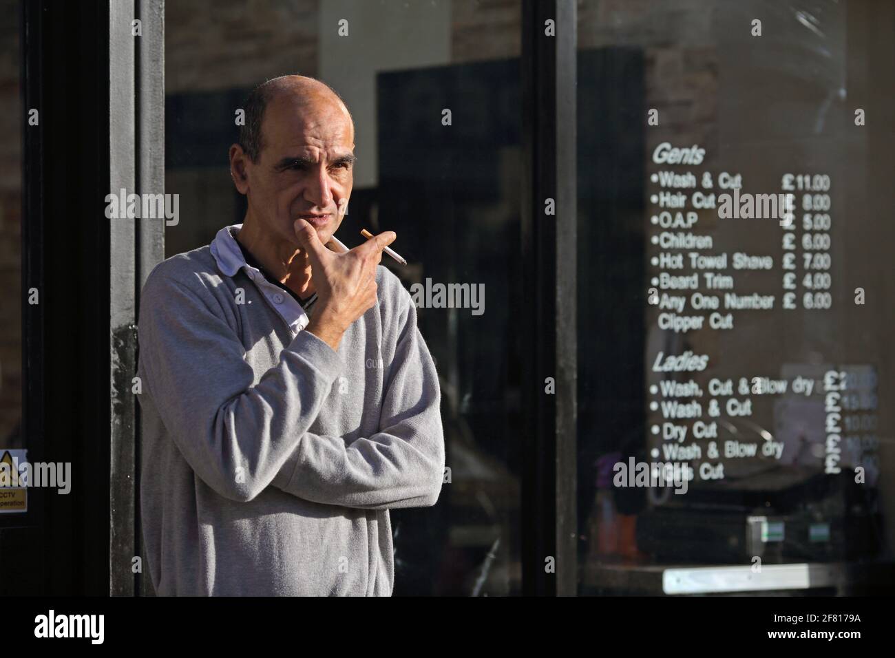 United Kingdom / London  /Hairdresser takes a cigarette break outside his barber shop in London . worker in London taking a cigarette break Stock Photo