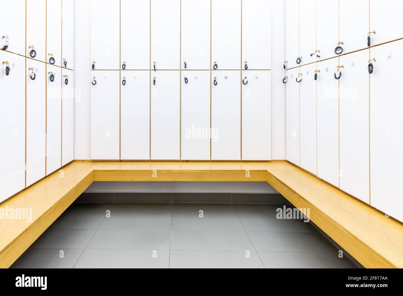 all white locker room with wooden bench Stock Photo