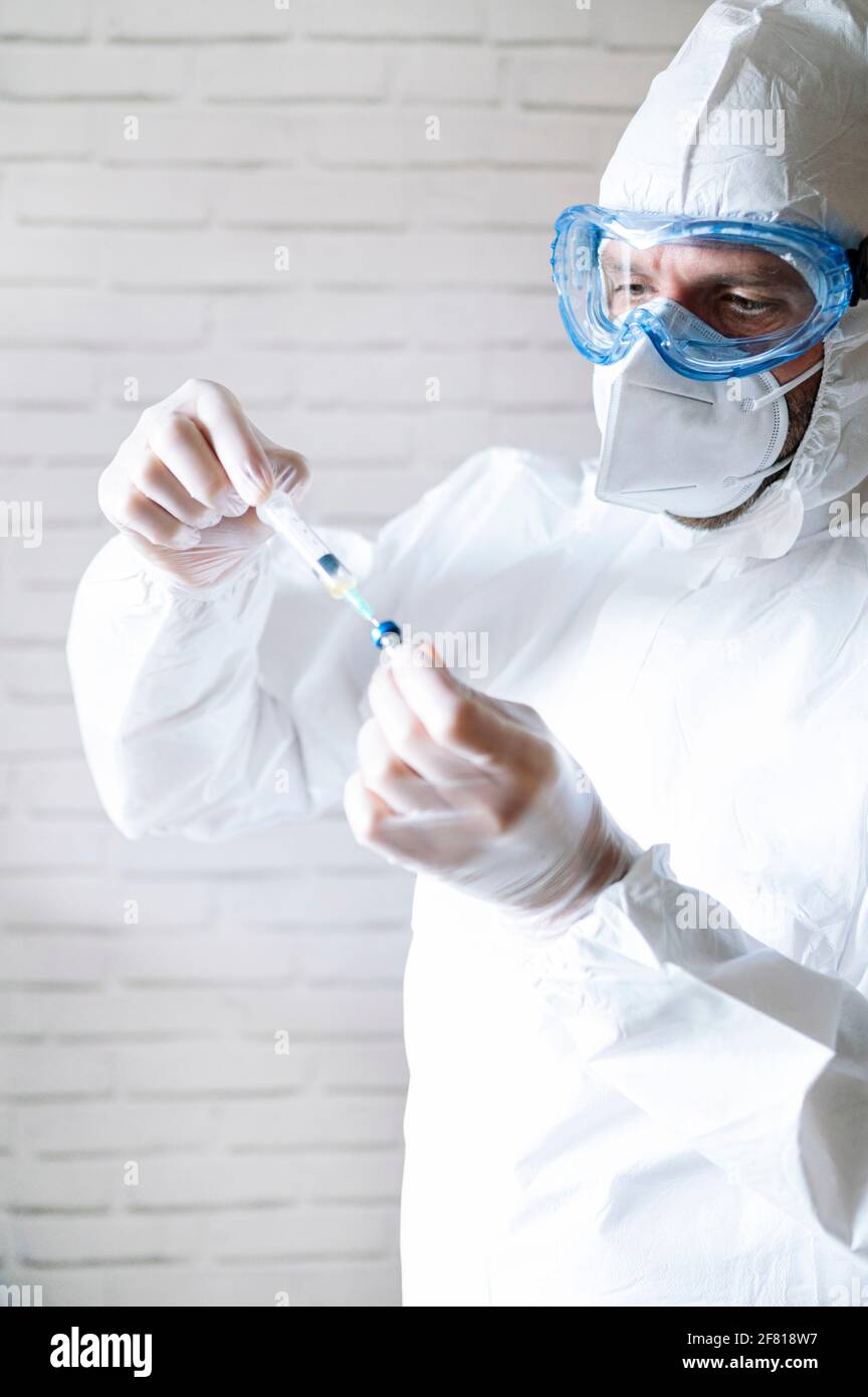 Male nurse in protective workwear filling injection Stock Photo