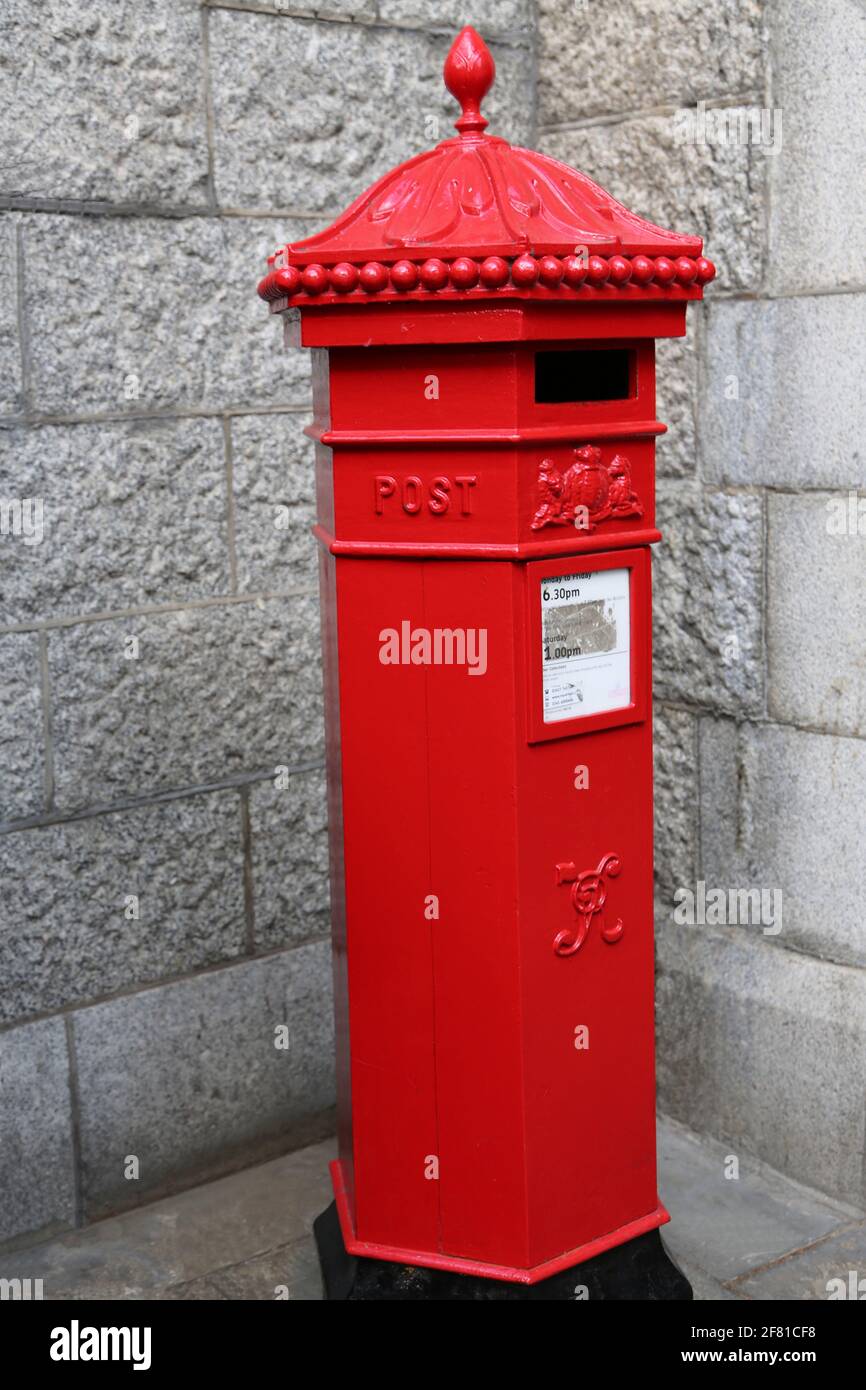 Vintage London post box with vintage coats of arms in red against a gray wall Stock Photo