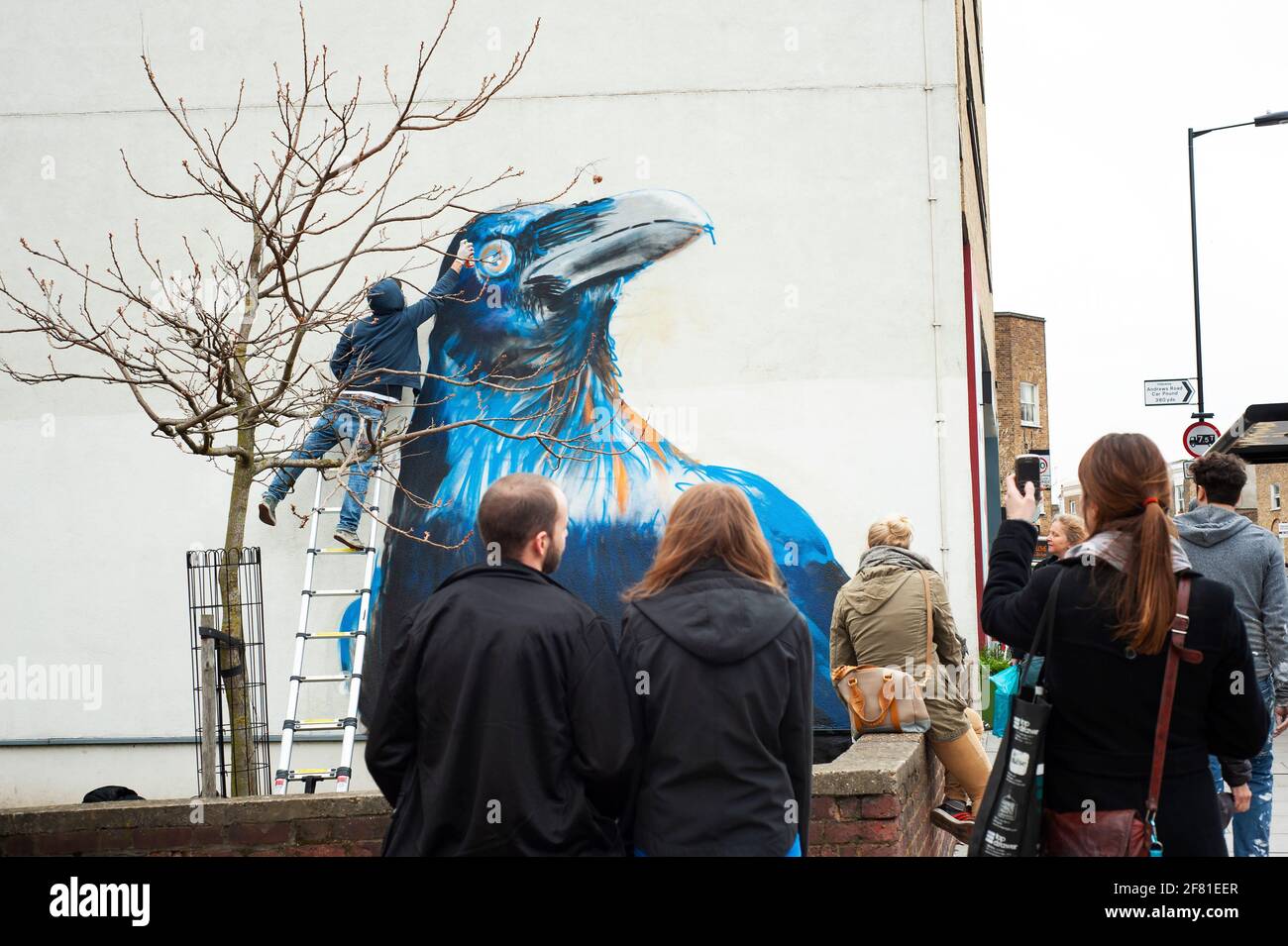 Graffiti artist Boe + Irony in action. Crow mural in the making with people watching on Whiston Road, East London, UK. Apr 2013 Stock Photo