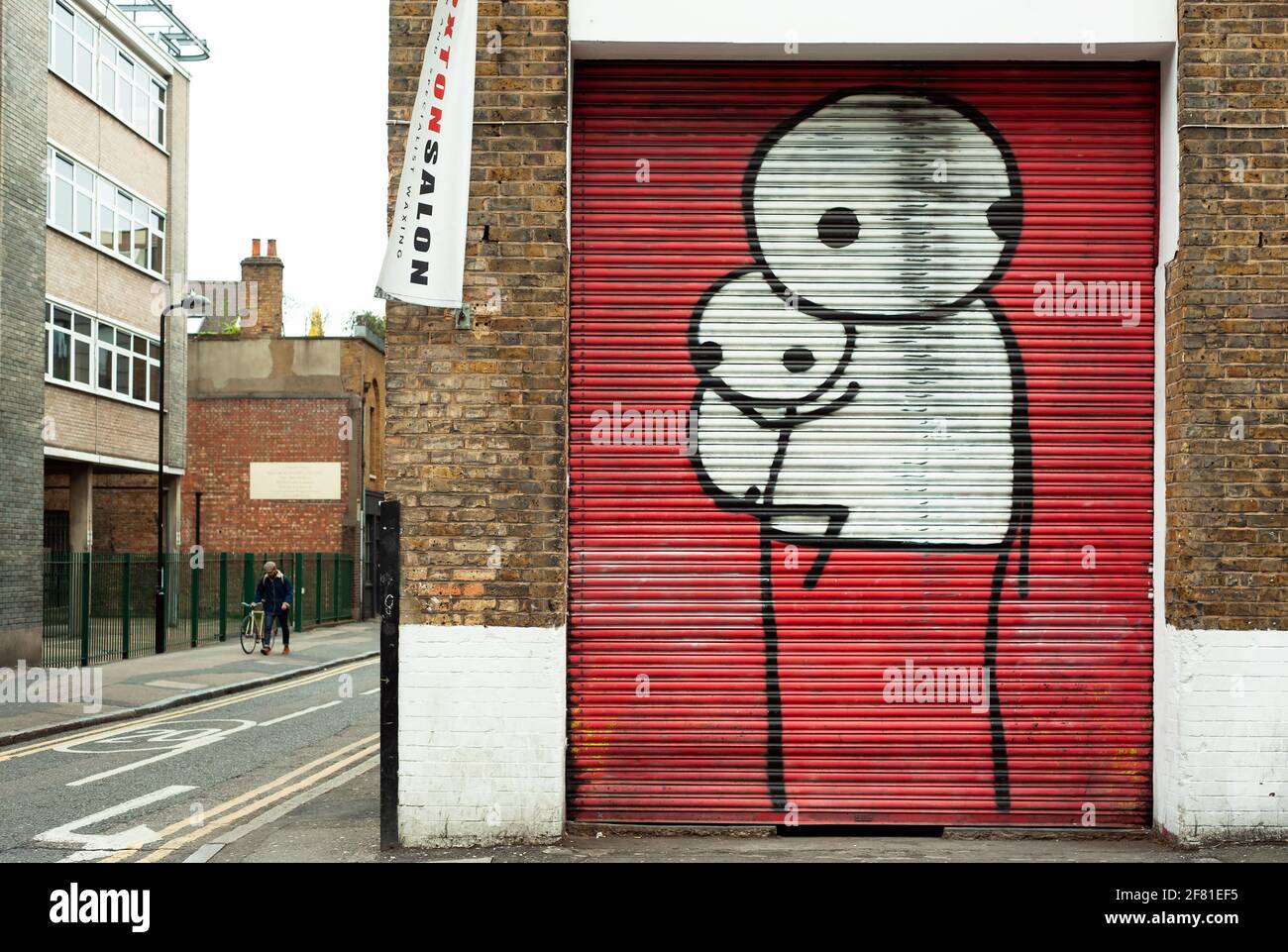 Stik's work (British graffiti artist based in London). Large stick figures on painted shutters. East London, UK. Apr 2013 Stock Photo