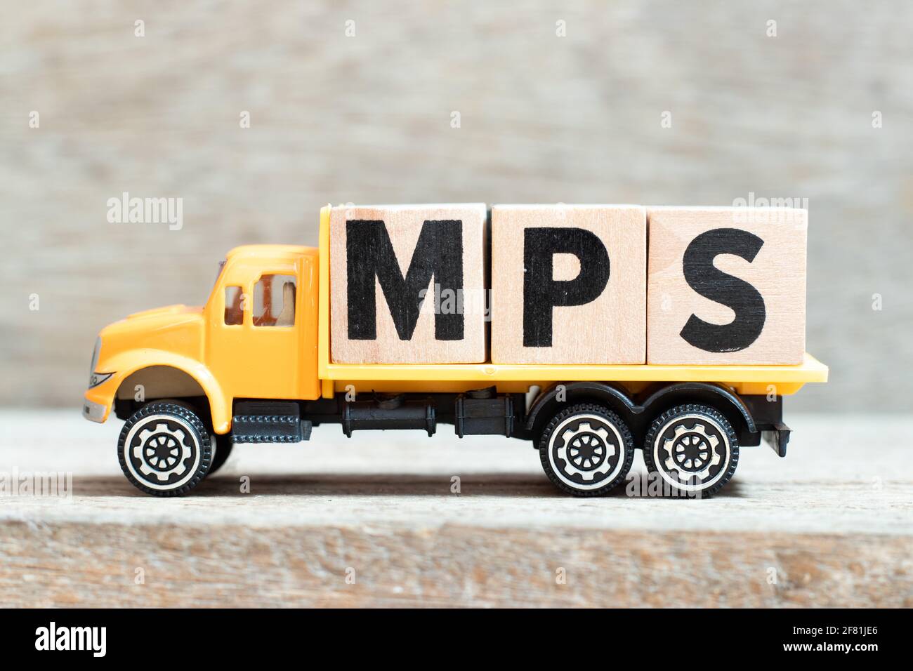 Toy truck hold alphabet letter block in word MPS (Abbreviation of Master Production Schedule or Mucopolysaccharidosis) on wood background Stock Photo
