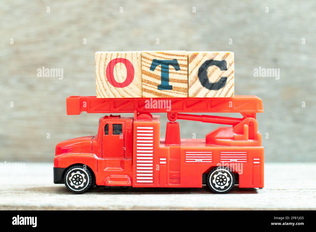 Fire ladder truck hold letter block in word OTC (Abbreviation of over the counter) on wood background Stock Photo