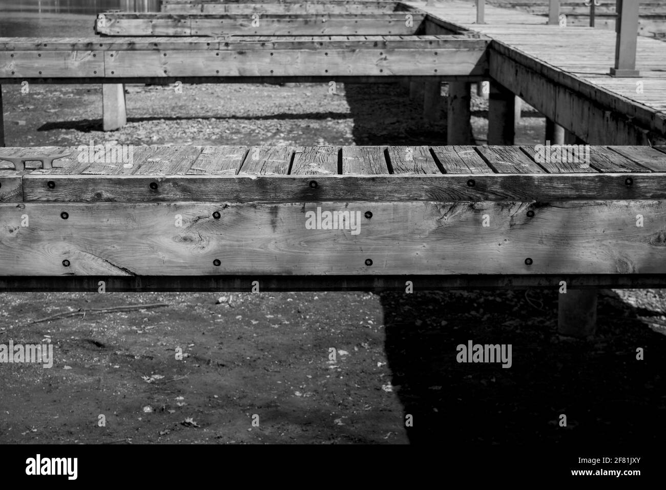 Black and white shot of the wooden boat dock with multiple berths at Dow's Lake Pavilion when the lake is emptied of water in winter. Ottawa, Ontario. Stock Photo