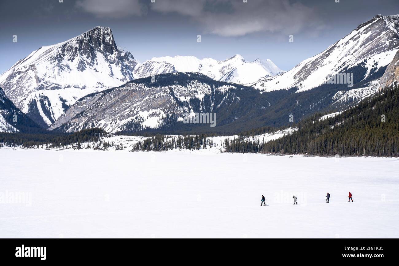 A group of people crossing a frozen lake wearing snowshoes in Kananaskis Alberta Canada Stock Photo