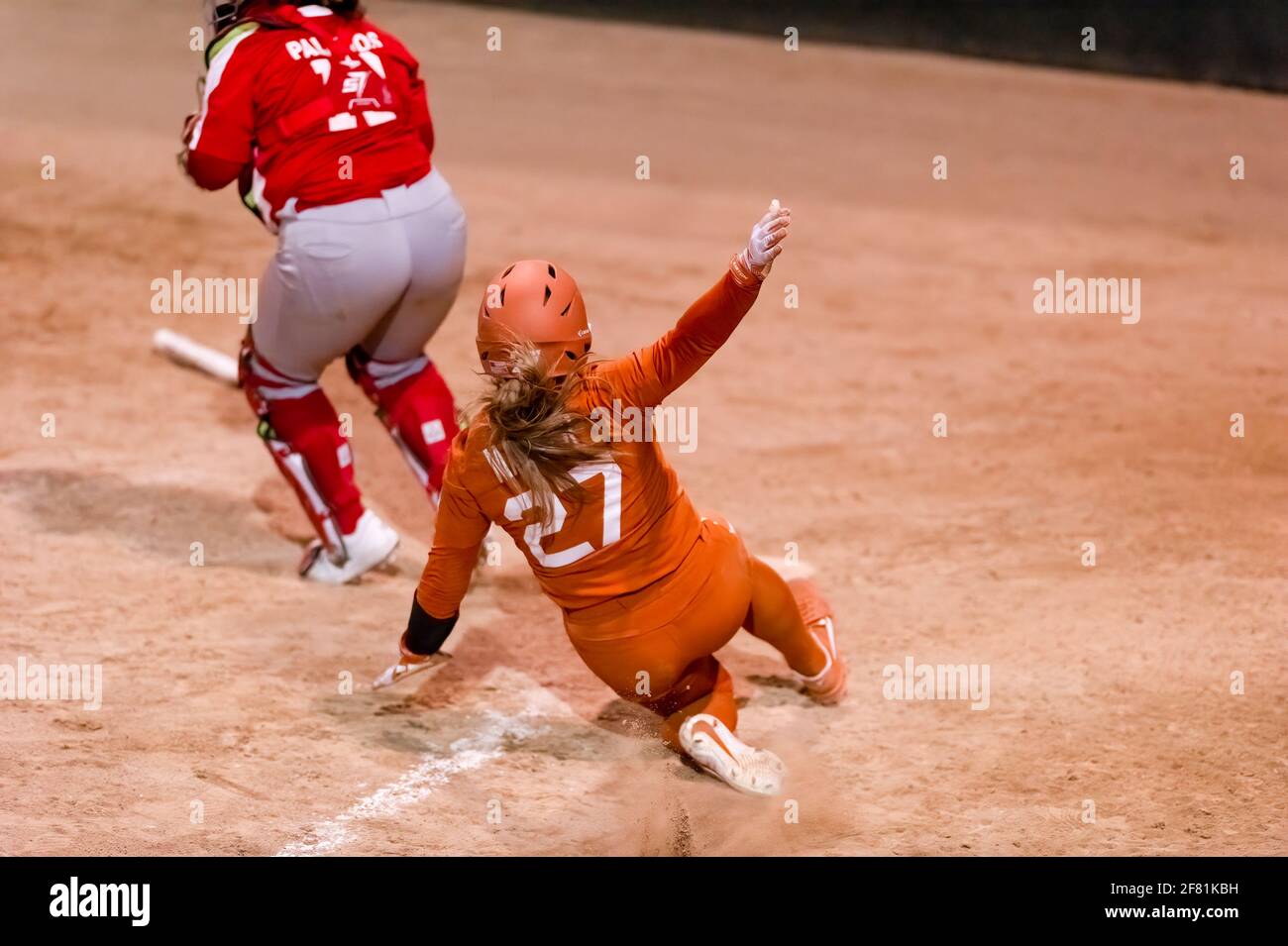 A Texas Longhorn Player is Sliding Into Home Plate Scoring A Run Stock Photo