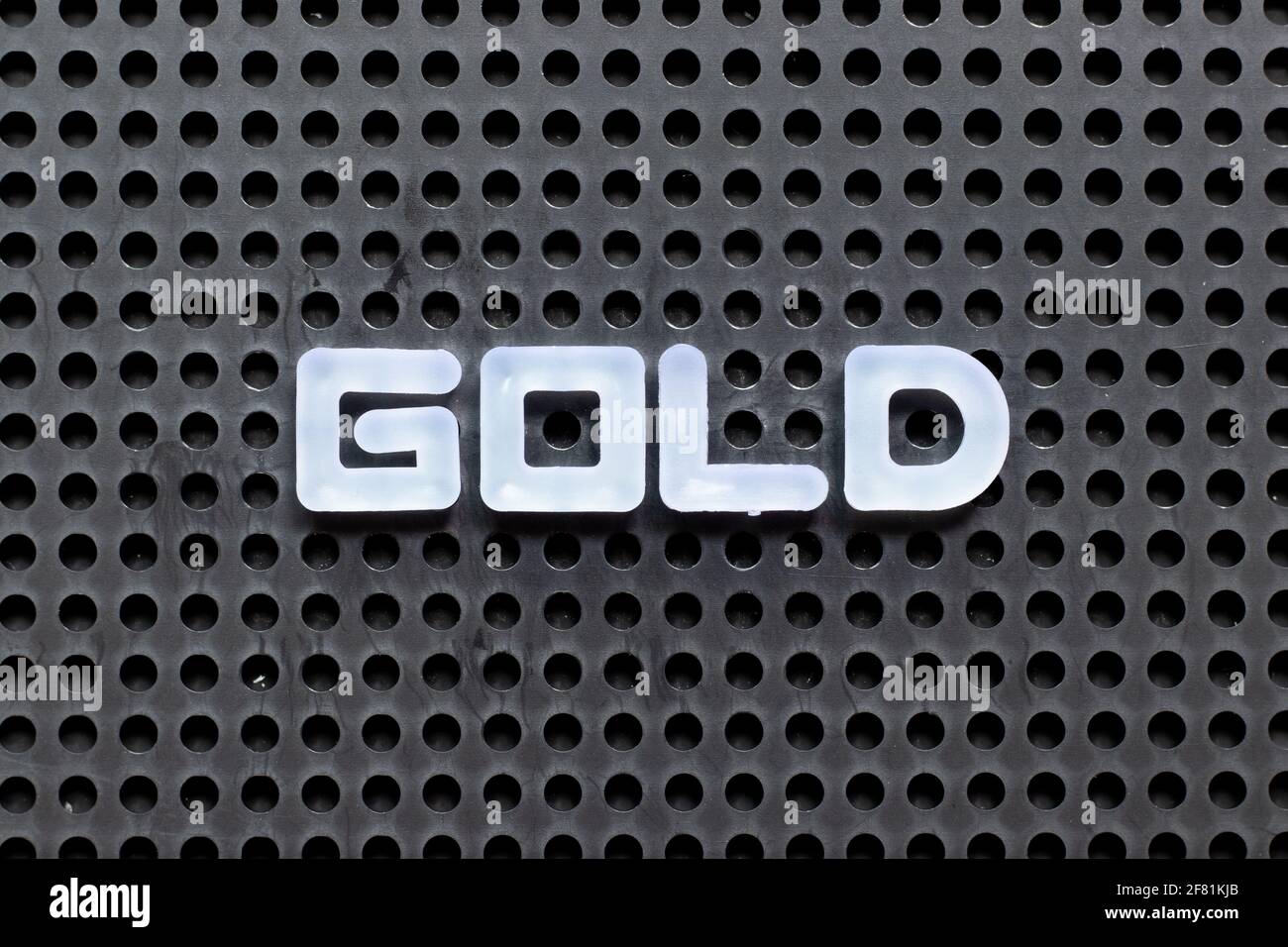 White color letter in word gold on black pegboard background Stock
