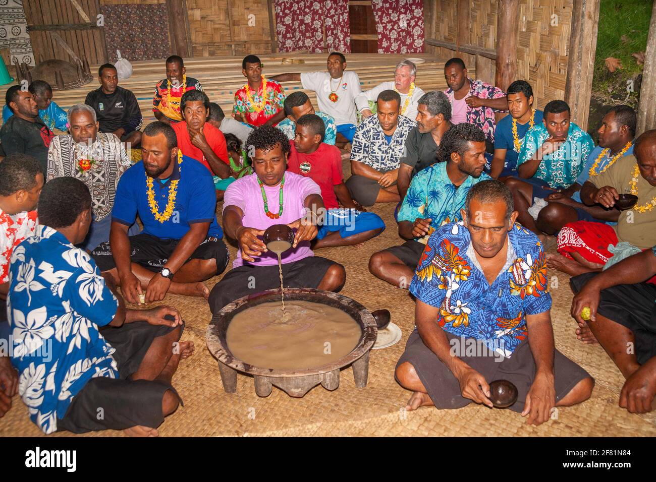Seated around the kava bowl, local Fijians prepare to dish out this traditional drink, in a small island village in Fiji. Stock Photo