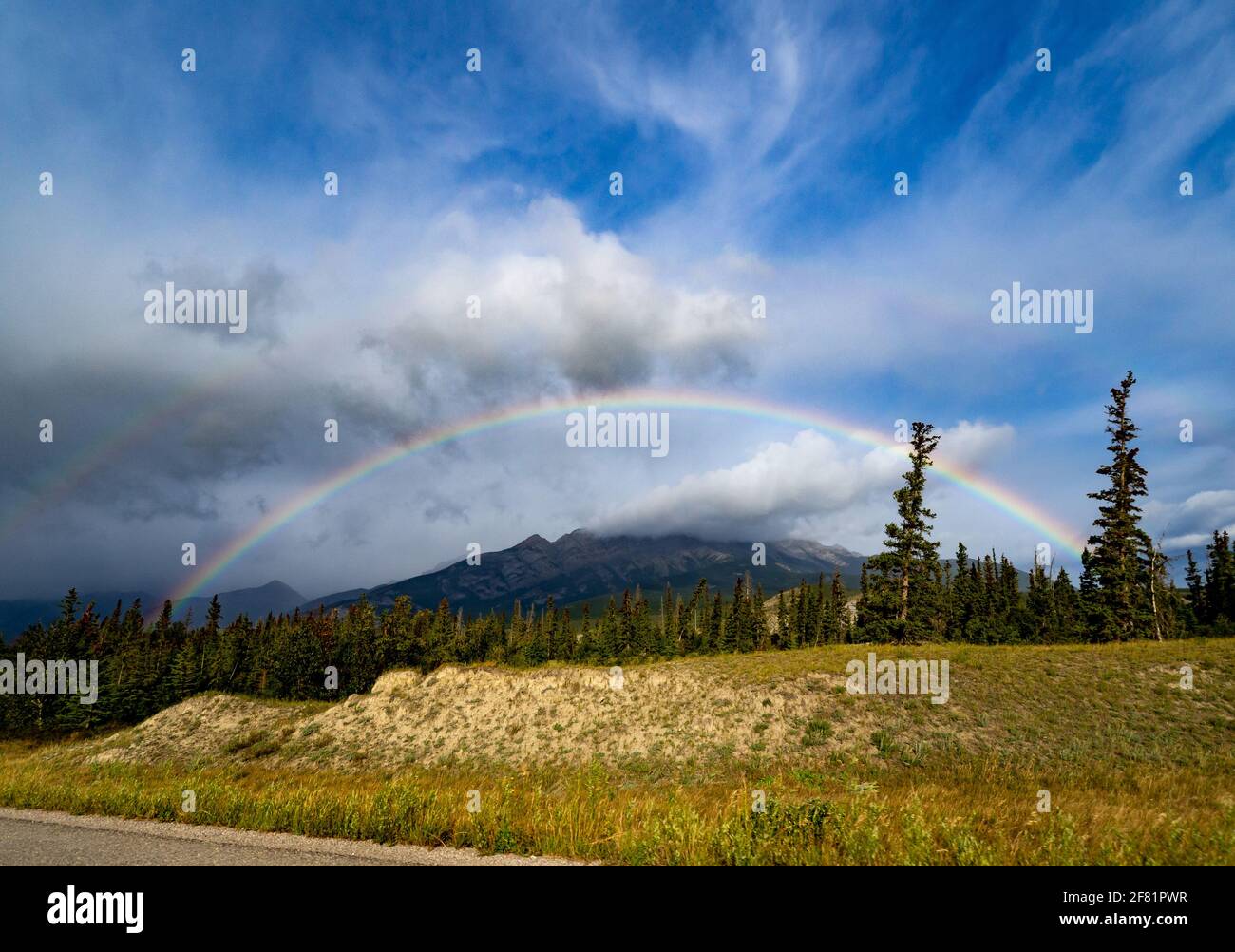 Full rainbow in summer with blue sky and clouds with grass Stock Photo ...