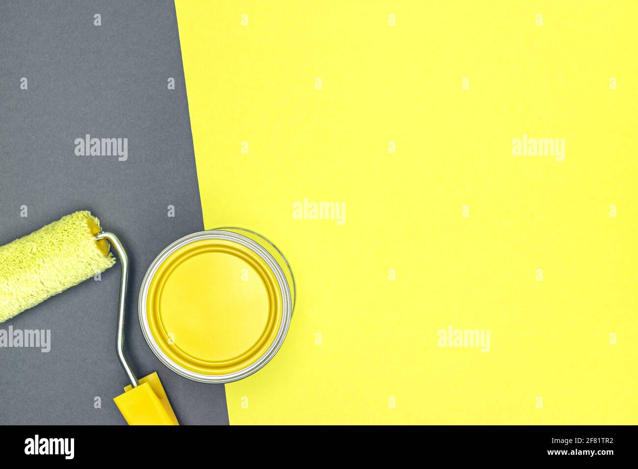 can of yellow paint and paint roller on yellow and gray background. house renovation concept. top view. Stock Photo