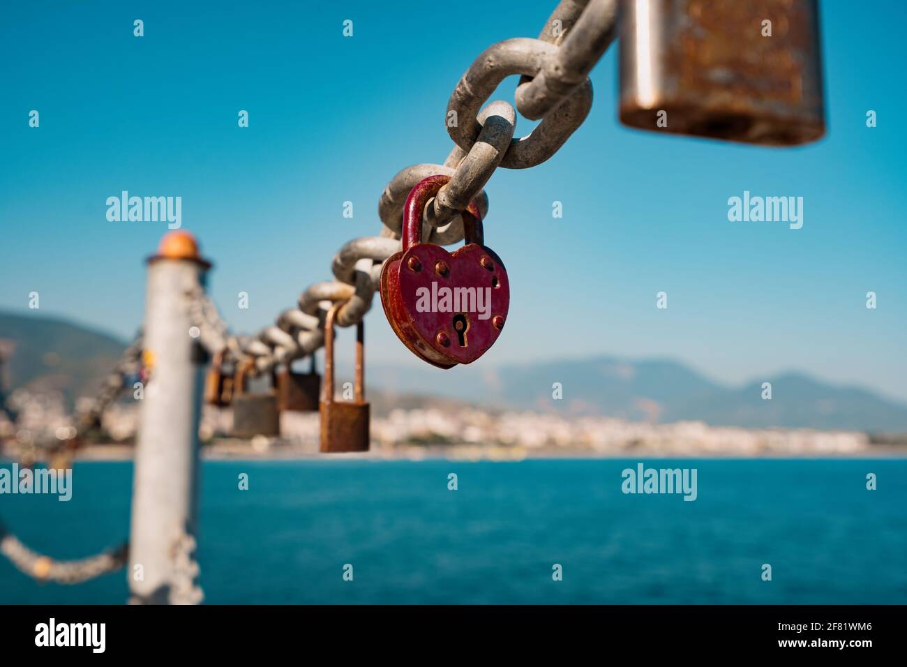 Red heart padlock on chain in front of blue sea and lighthouse, symbol ...
