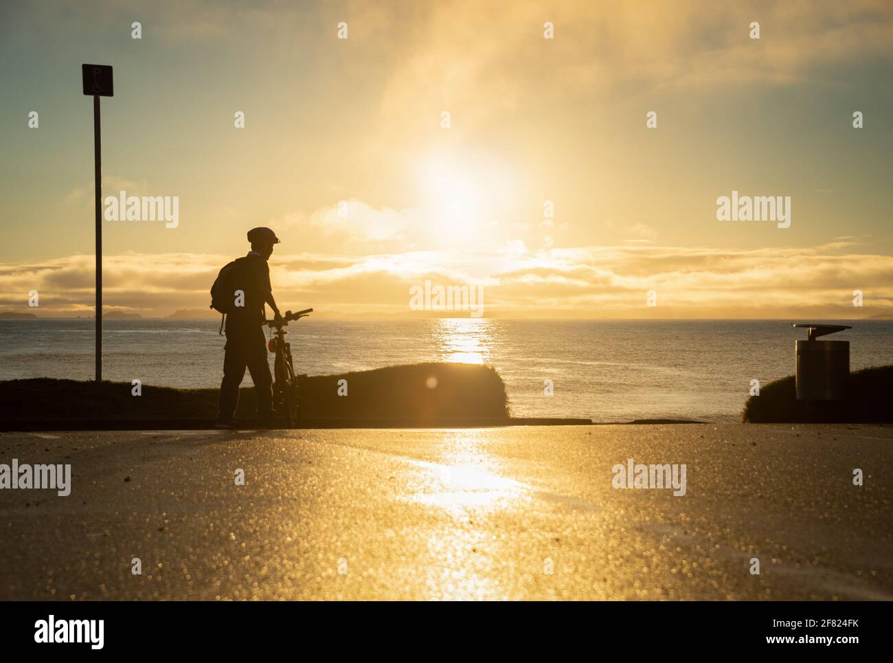 Silhouette image of a cyclist getting ready to ride on the beach at sunrise Stock Photo