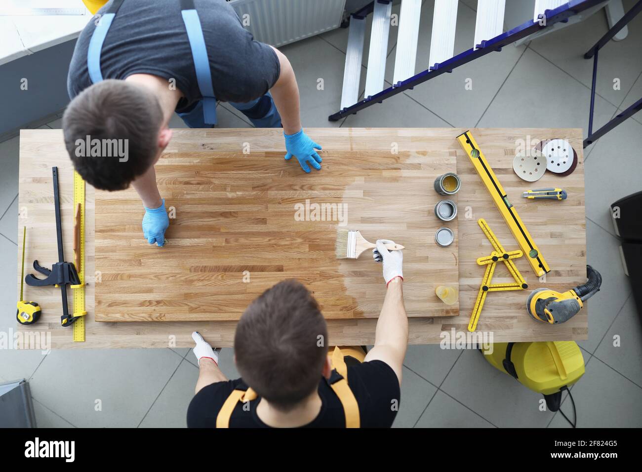 Two male construction workers are covering wood floor with protective