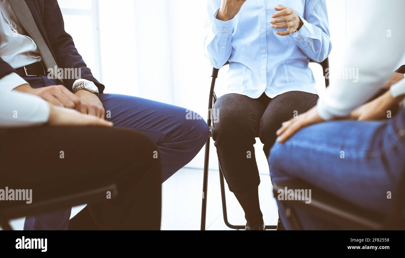 Group of people sitting in a circle during therapy in office. Meeting of business team participating in training Stock Photo