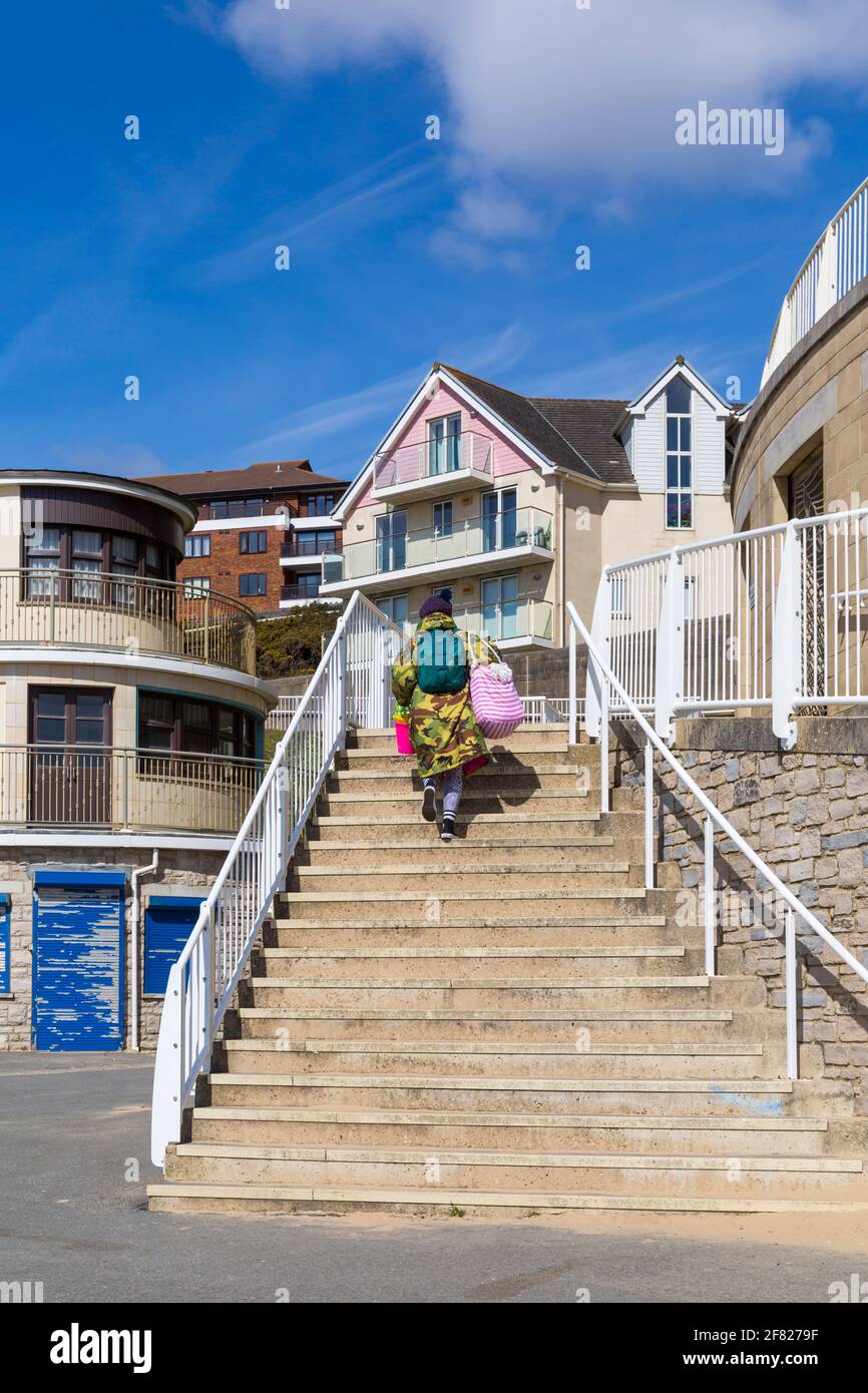 Woman climbing steps to seafront apartments at Boscombe, Bournemouth, Dorset UK in April Stock Photo