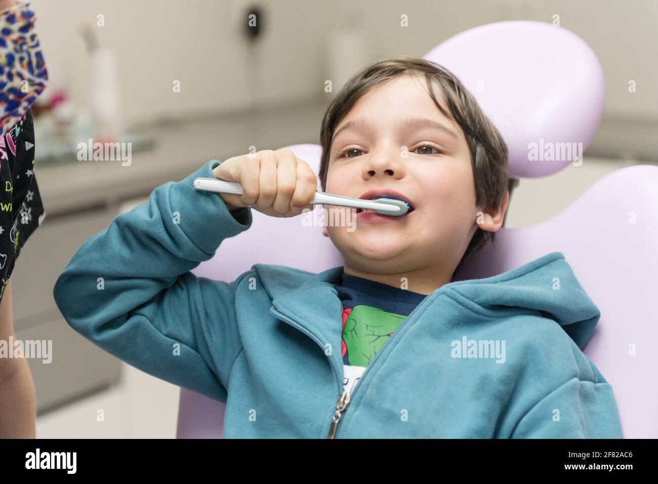 Young boy with teeth brush practicing how to brush teeth in dental