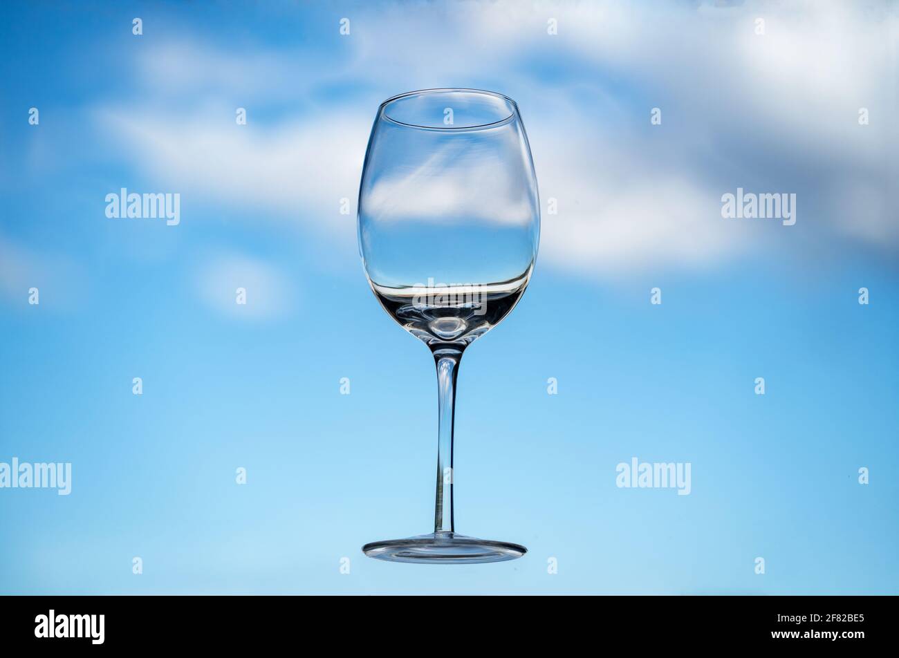 Floating empty wine glass in front of a blue sky with fluffy clouds Stock  Photo - Alamy