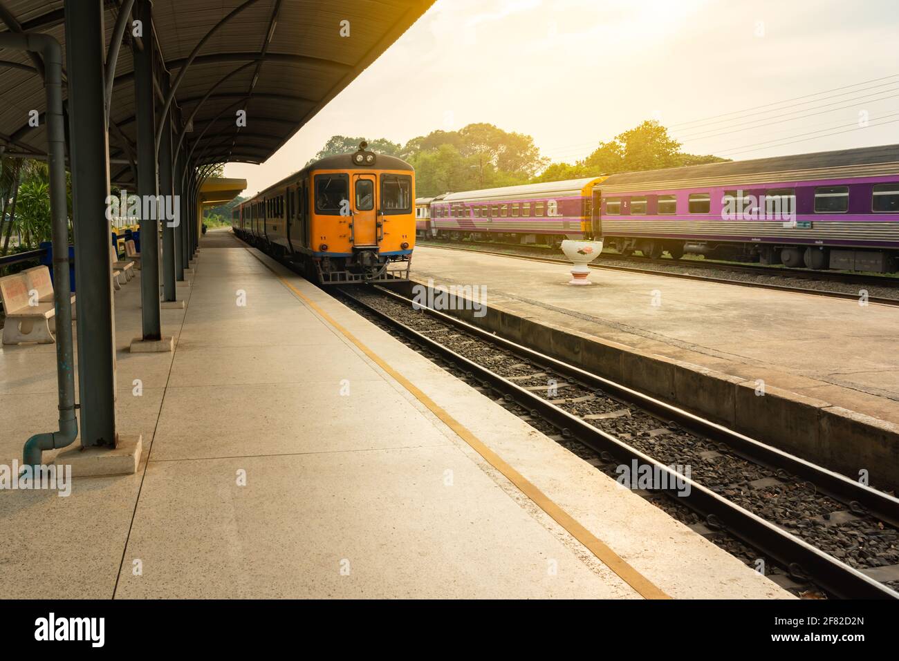 Thai local train on railway at sunset. Stock Photo