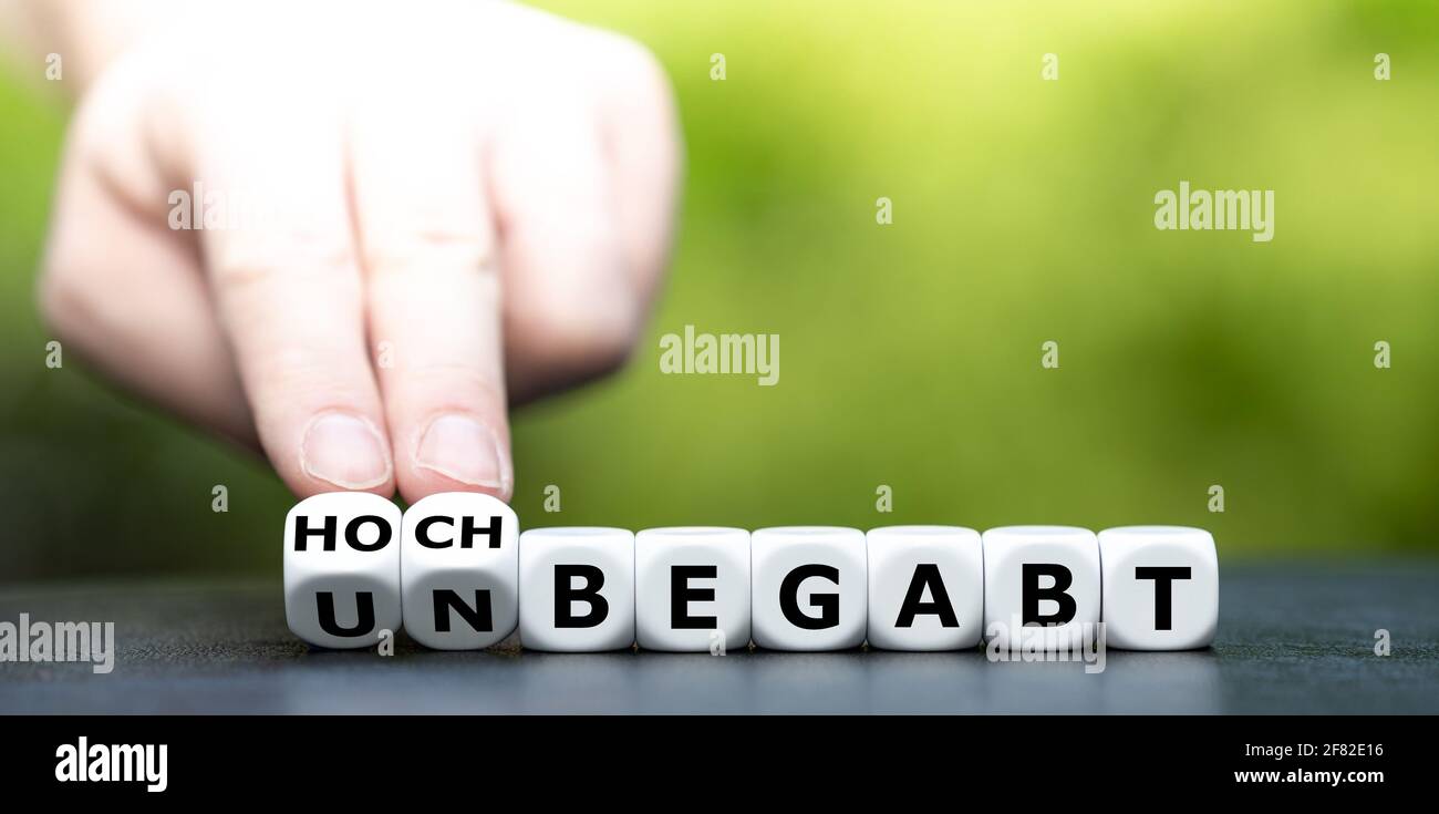 Hand turns dice and changes the German expression 'unbegabt' (unskilled) to 'hochbegabt' (highly sklilled). Stock Photo