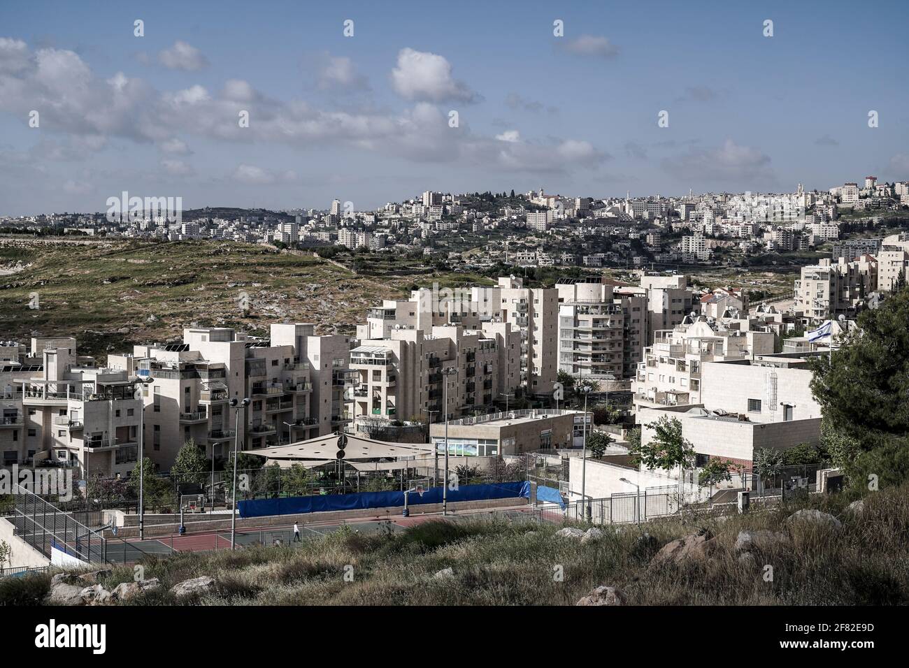 Jerusalem, Israel. 11th April, 2021. Construction is ongoing in Homat Shmuel, or Har Homa, in East Jerusalem, with the Palestinian city of Bethlehem depicted in the far background, on land expropriated in 1991, as a Jerusalem committee approves a plan for an additional 540 housing units. The Jewish neighborhood beyond the Green Line, the armistice demarcation line before the 1967 Six Day War that separates Israel and the West Bank, is considered an illegal Israeli settlement by much of the world. The plan is the first major building project across the pre 1967 boundaries since U.S. President B Stock Photo