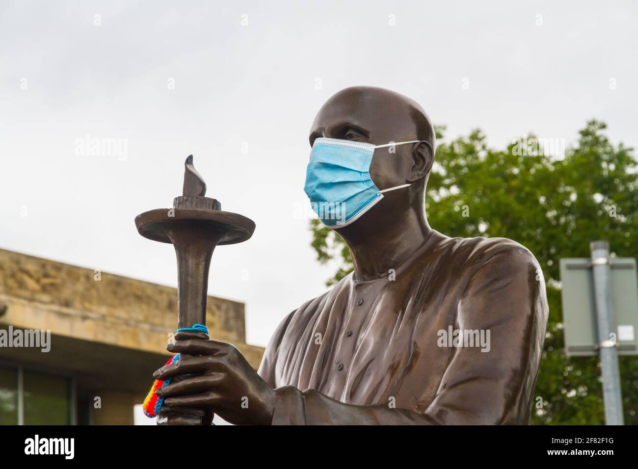 CARDIFF, WALES – JULY 7 2020: during coronavirus pandemic surgical mask on the World Harmony Peace Statue of Sri Chinmoy with a torch Stock Photo