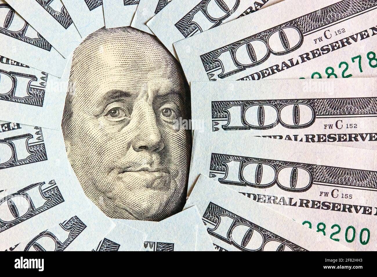 A lot of folded one hundred 100 USD bills layed like vintage sun face beams around Benjamin Franklin portrait from 100 dollar US bill american Stock Photo