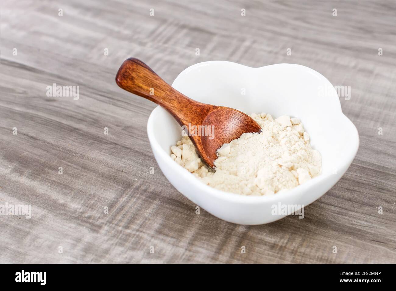 A closeup of a wooden spoon with garlic powder in a bowl Stock Photo