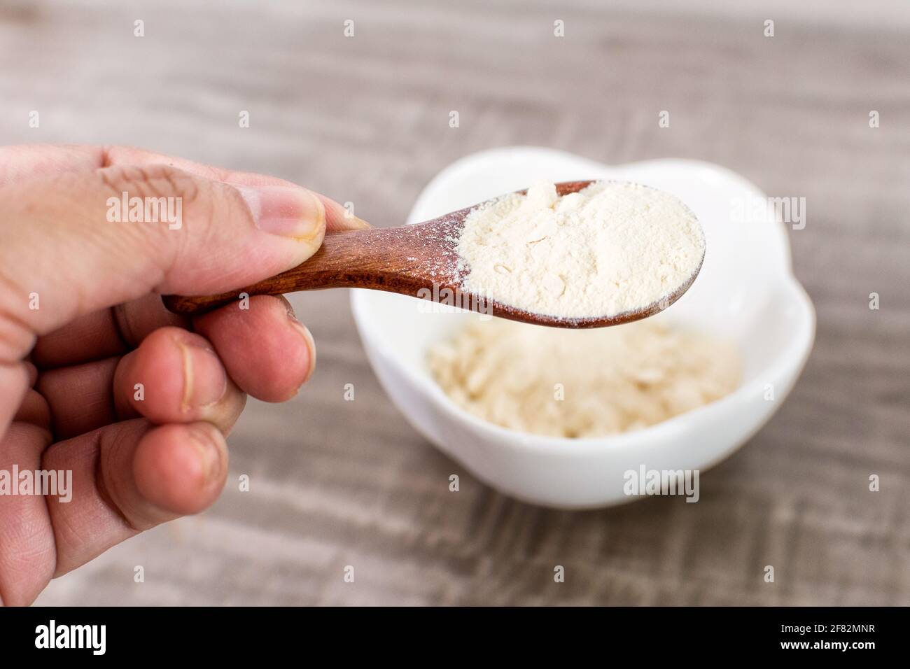 A closeup of a hand holding a wooden spoon with garlic powder. Stock Photo