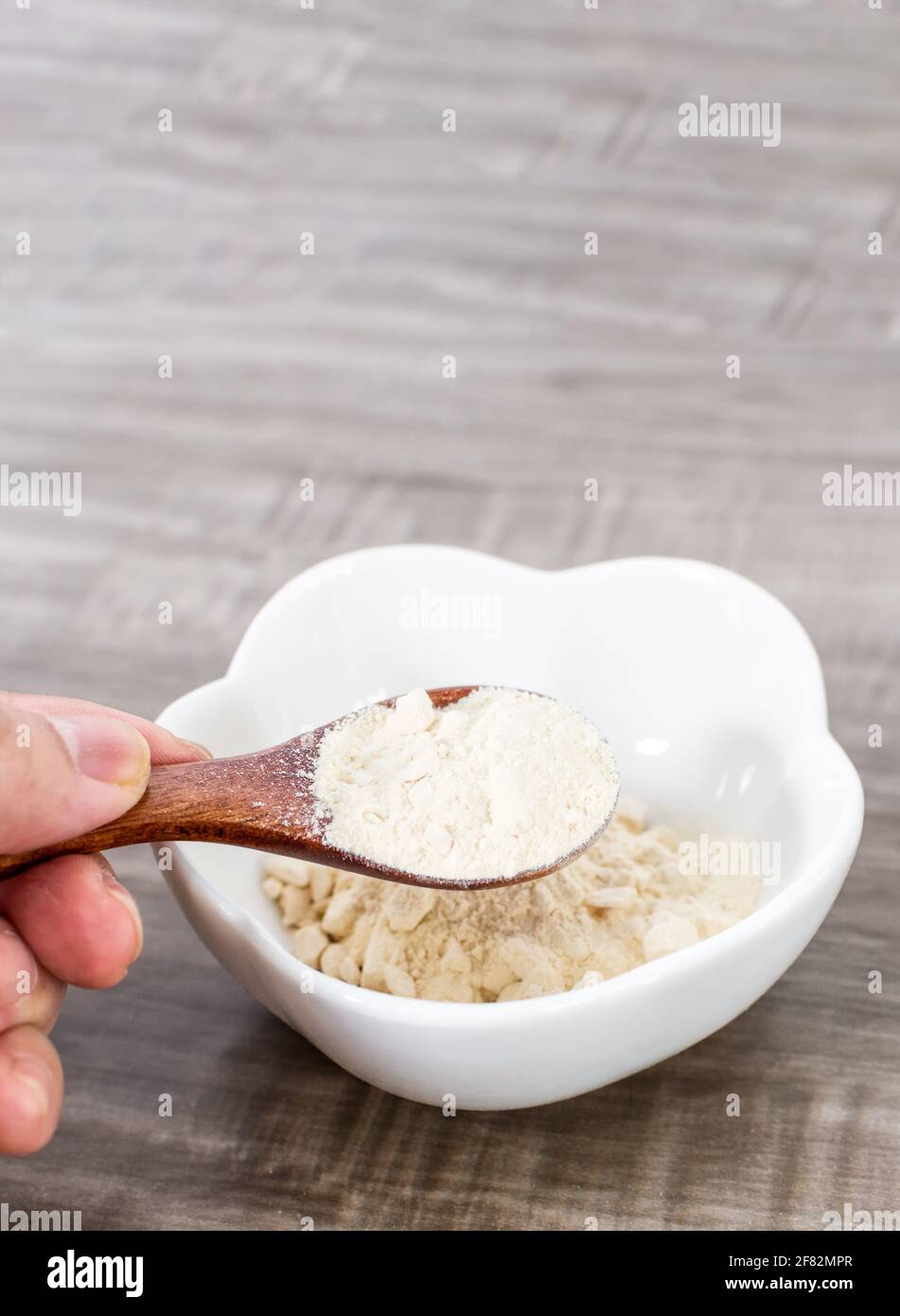 A closeup of a hand holding a wooden spoon with garlic powder Stock Photo