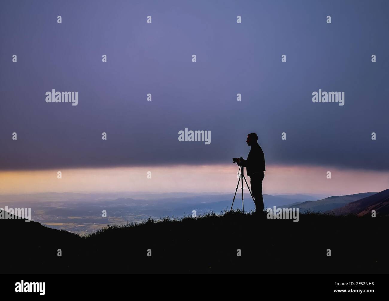 Silhouette of photographer with camera on tripod at cloudy sunset in ...