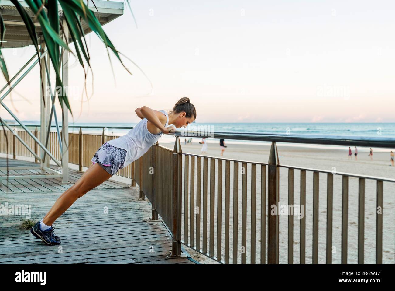 Young beautiful sportive woman doing exercises on beach Stock Photo