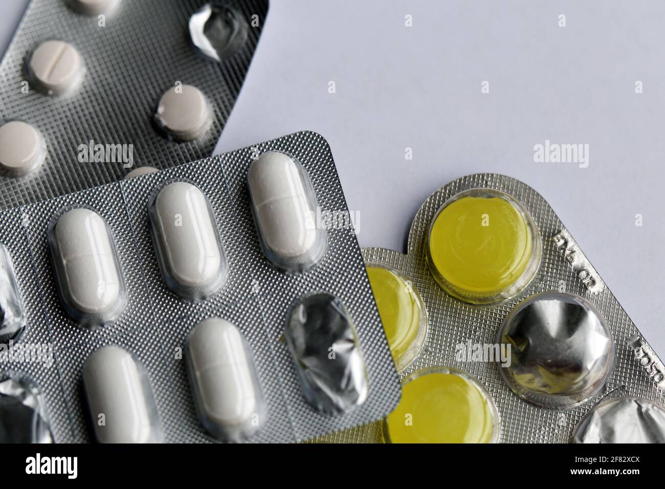 Plenty of different medications - pills for sore throat, painkillers and  more photographed on a white table. Good drugs for cold and flu. Closeup  Stock Photo - Alamy