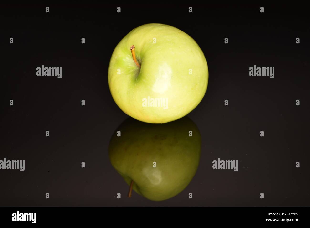 One organic bright green, ripe, juicy, tasty apple , close-up, on a black background. Stock Photo