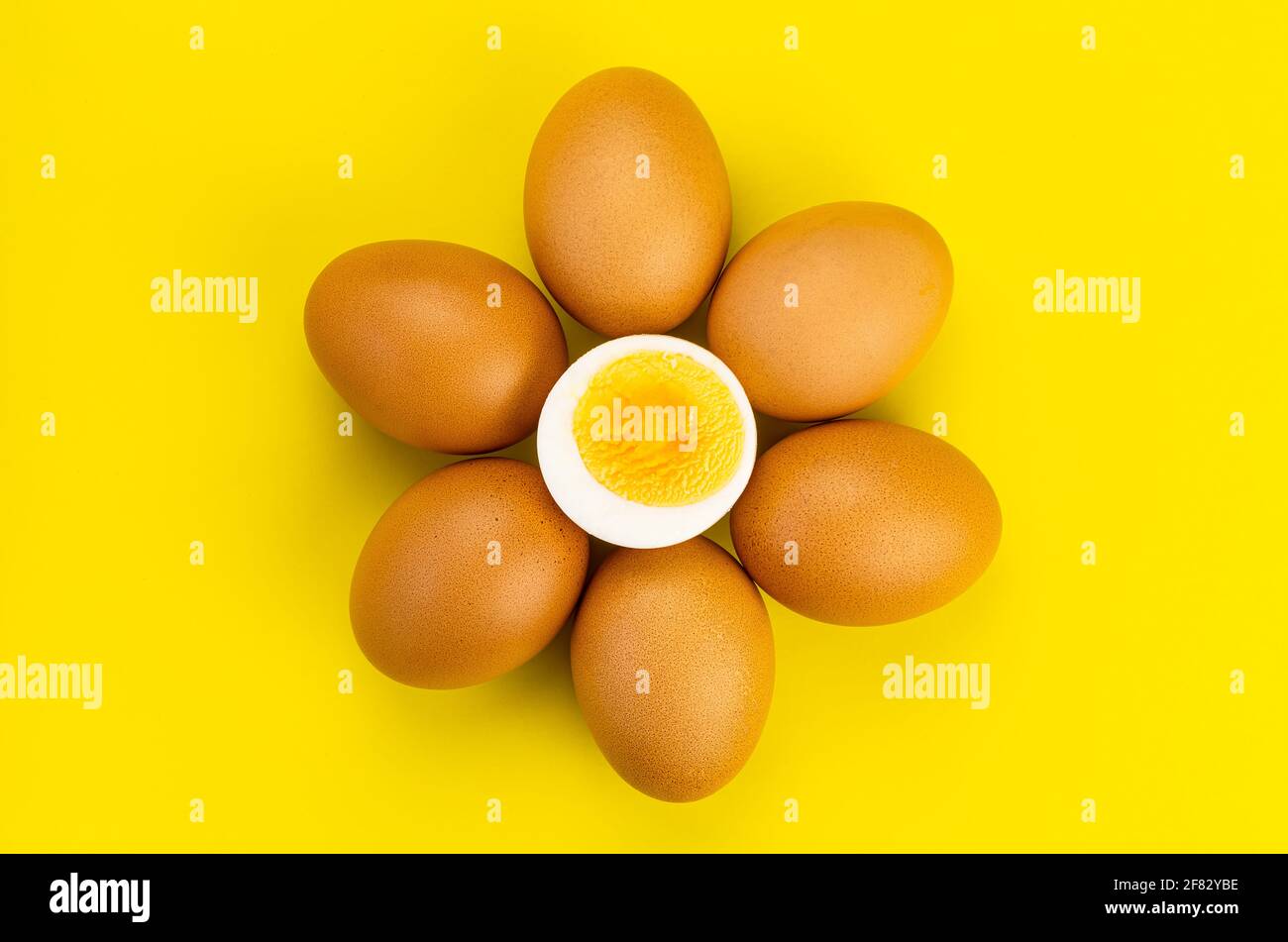 Top view group of whole chicken eggs and a half boiled egg deocorated on yellow background Stock Photo