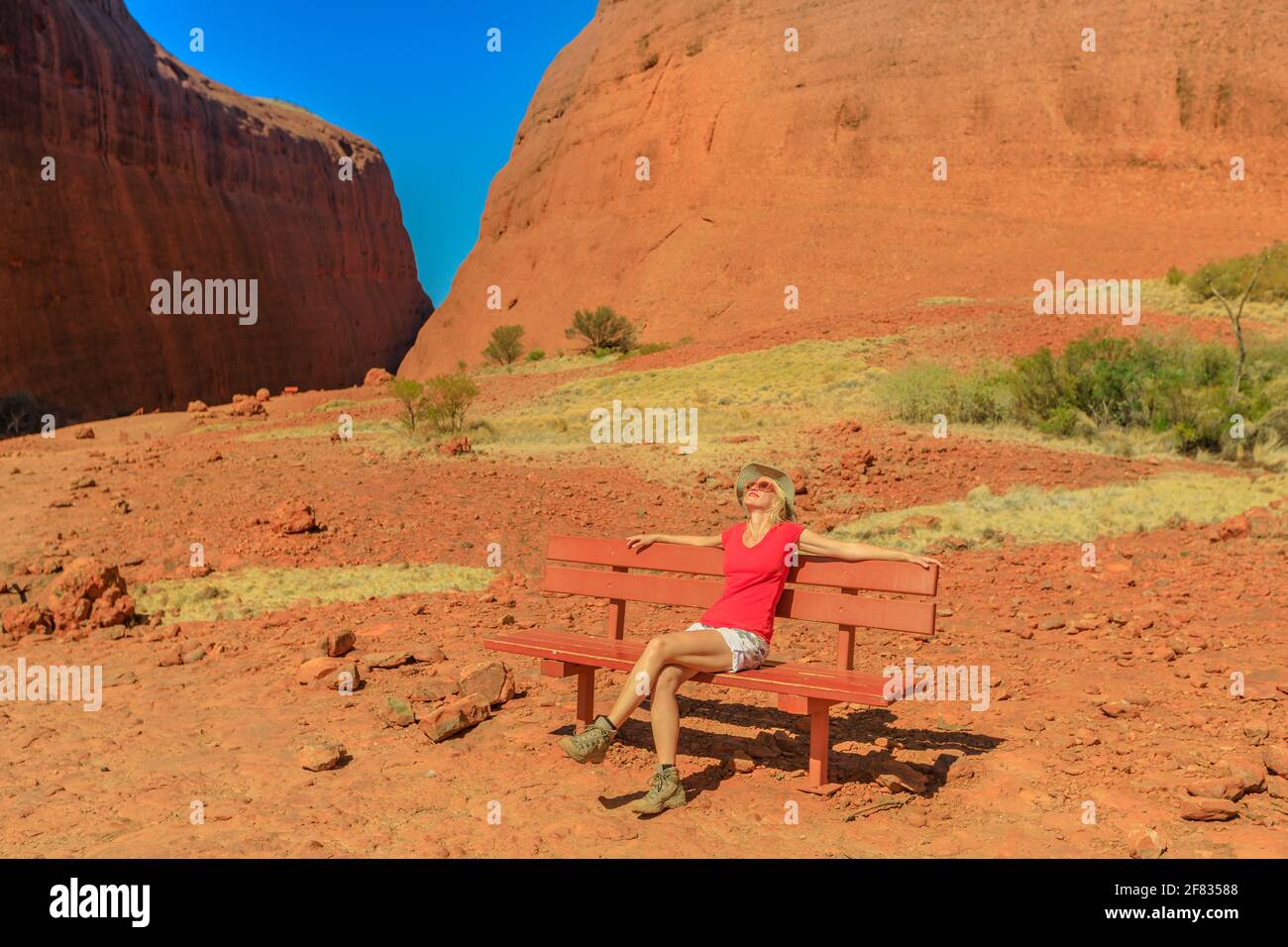 Tourist woman sitting on a bench at entrance of the gorge along Walpa Gorge Walk in Uluru-Kata Tjuta National Park. Australian outback Red Center Stock Photo