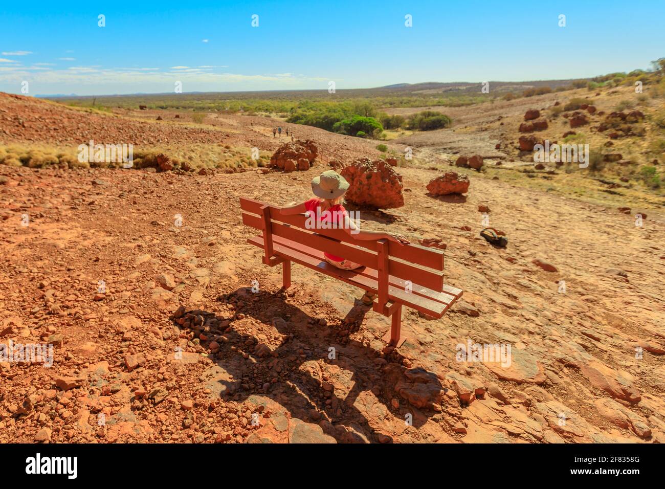 Tourist woman relaxing on a bench at entrance of the gorge along Walpa Gorge Walk in Uluru-Kata Tjuta National Park. Australian outback Red Center Stock Photo