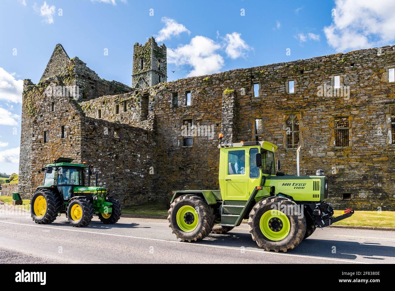 Timoleague, West Cork, Ireland. 11th Apr, 2021. Two vintage tractors pass the Franciscan Friary in the West Cork village of Timoleague on a beautiful sunny day. The tractors, A 1990 Mercedes MB Trac 1100 and a 1992 John Deere 2850 are owned by farmers David Deasy and Paudie O'Leary, who both live in Timoleague. Credit: AG News/Alamy Live News Stock Photo