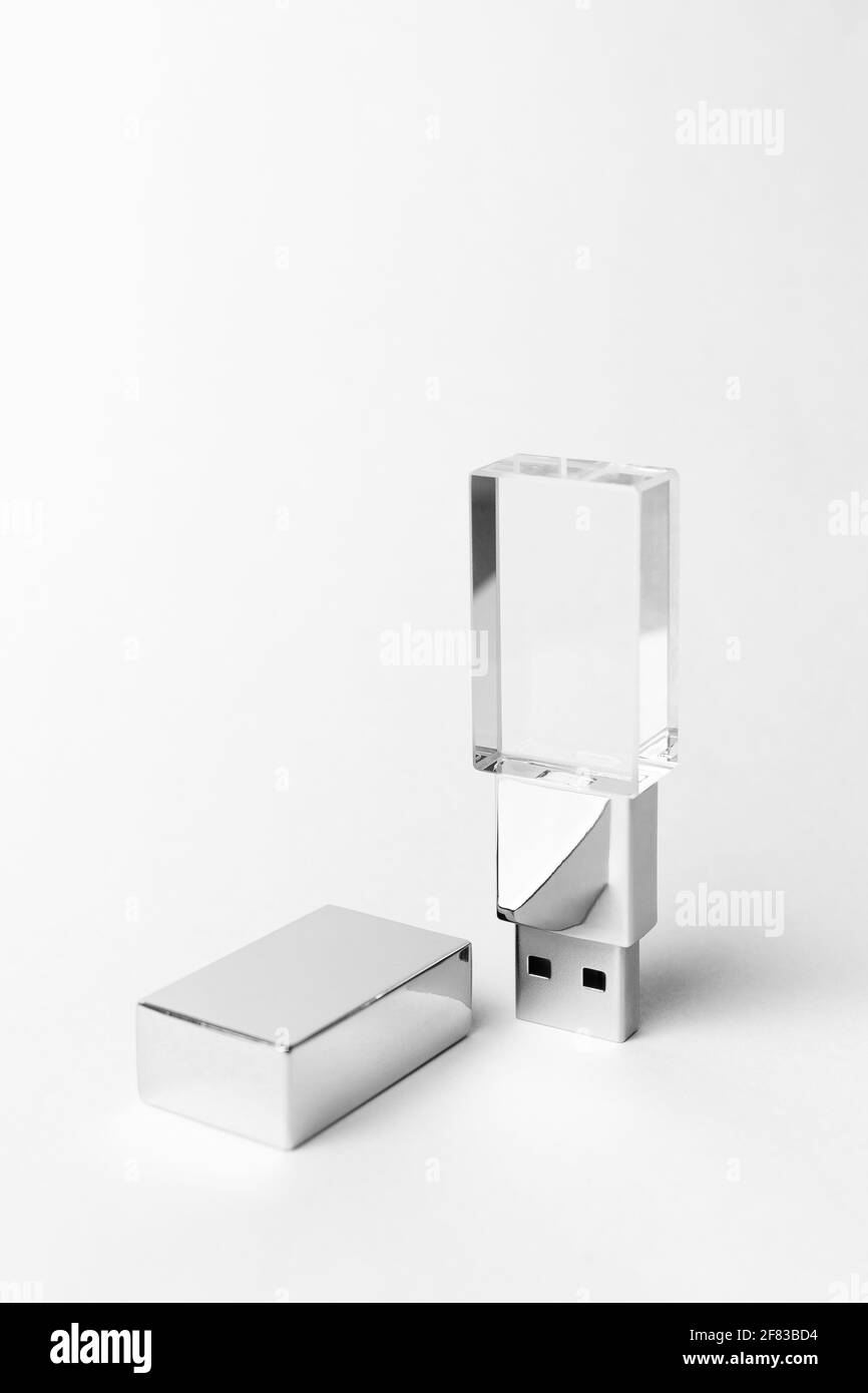 Glass USB stick with a metal cover on a gray background. Copy space. Vertical close-up photo. Stock Photo