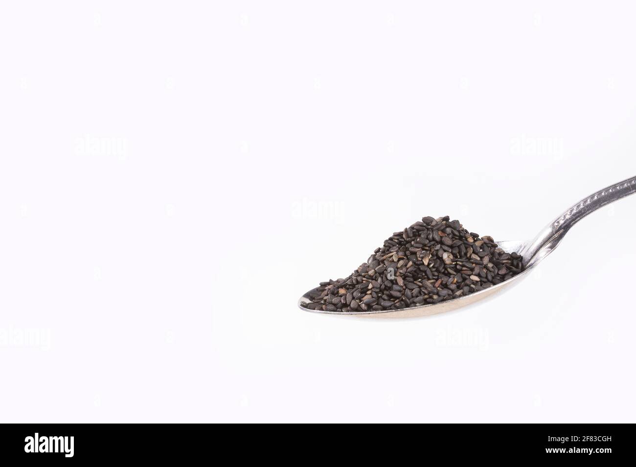 Black sesame seeds in the spoon Sesamum indicum. White background
