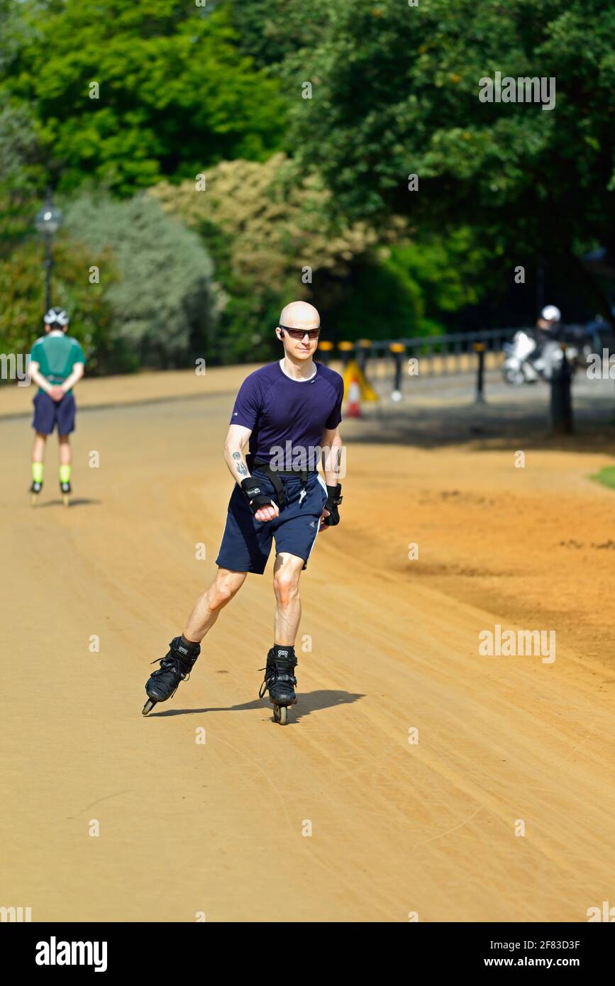 Shaven head young man inline skating, rollerblading, Hyde Park, London, United Kingdom Stock Photo