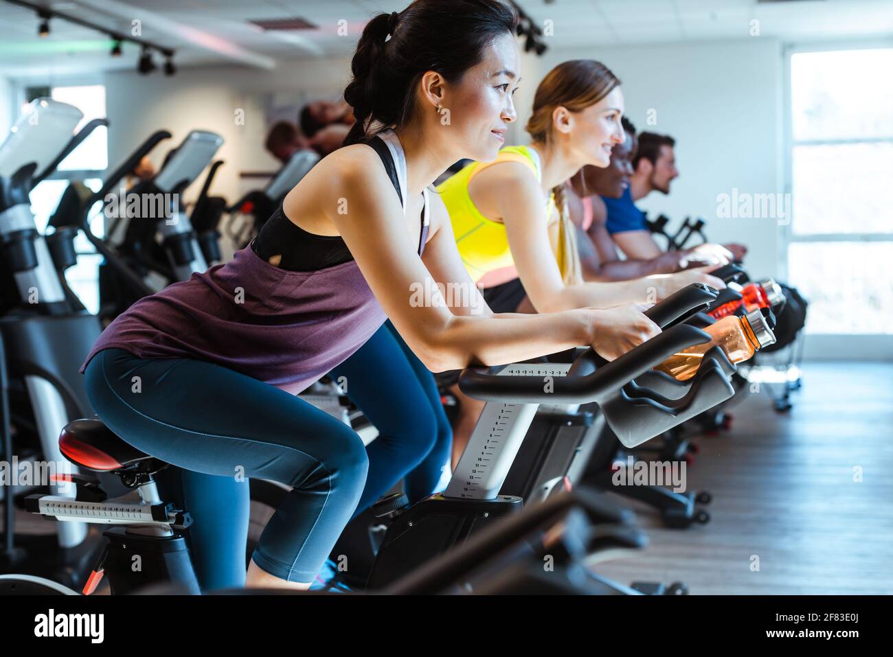 Asian woman and her friends on fitness bike in gym Stock Photo