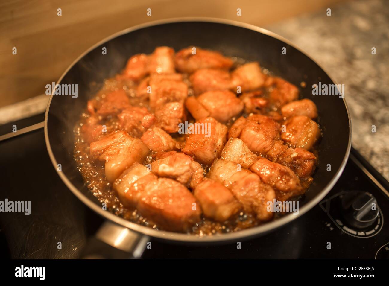 Caramelized pork cooking in a pan under the yellow light Stock Photo
