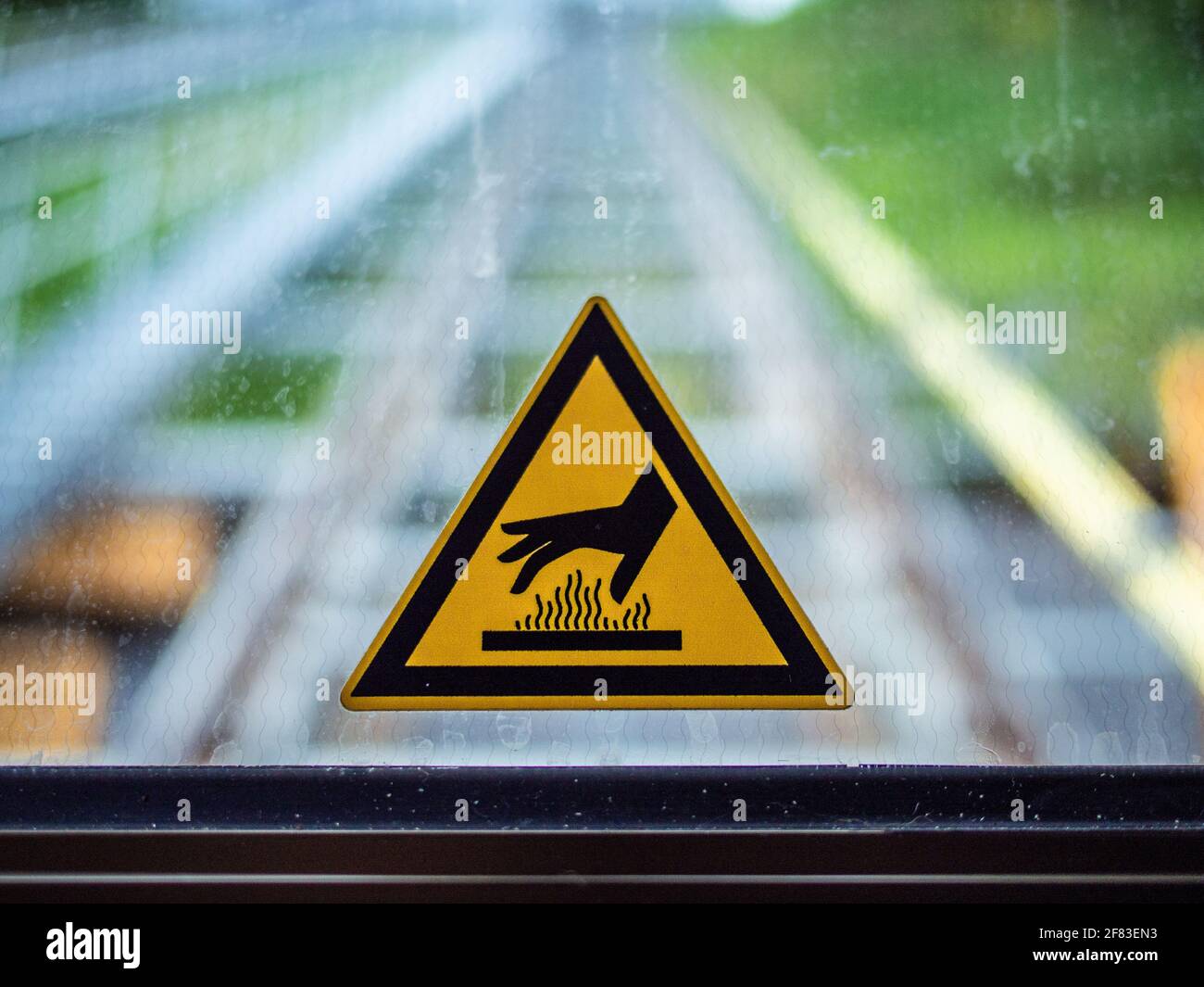 Yellow triangle shape sticker on a window with a hand and heat symbol Stock Photo