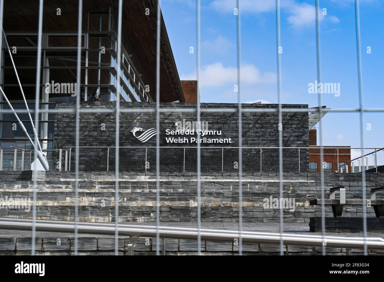 Cardiff Bay, Wales - April 2021: Sign on the wall of the Welsh Parliament building seen behind wire mesh fencing. Stock Photo