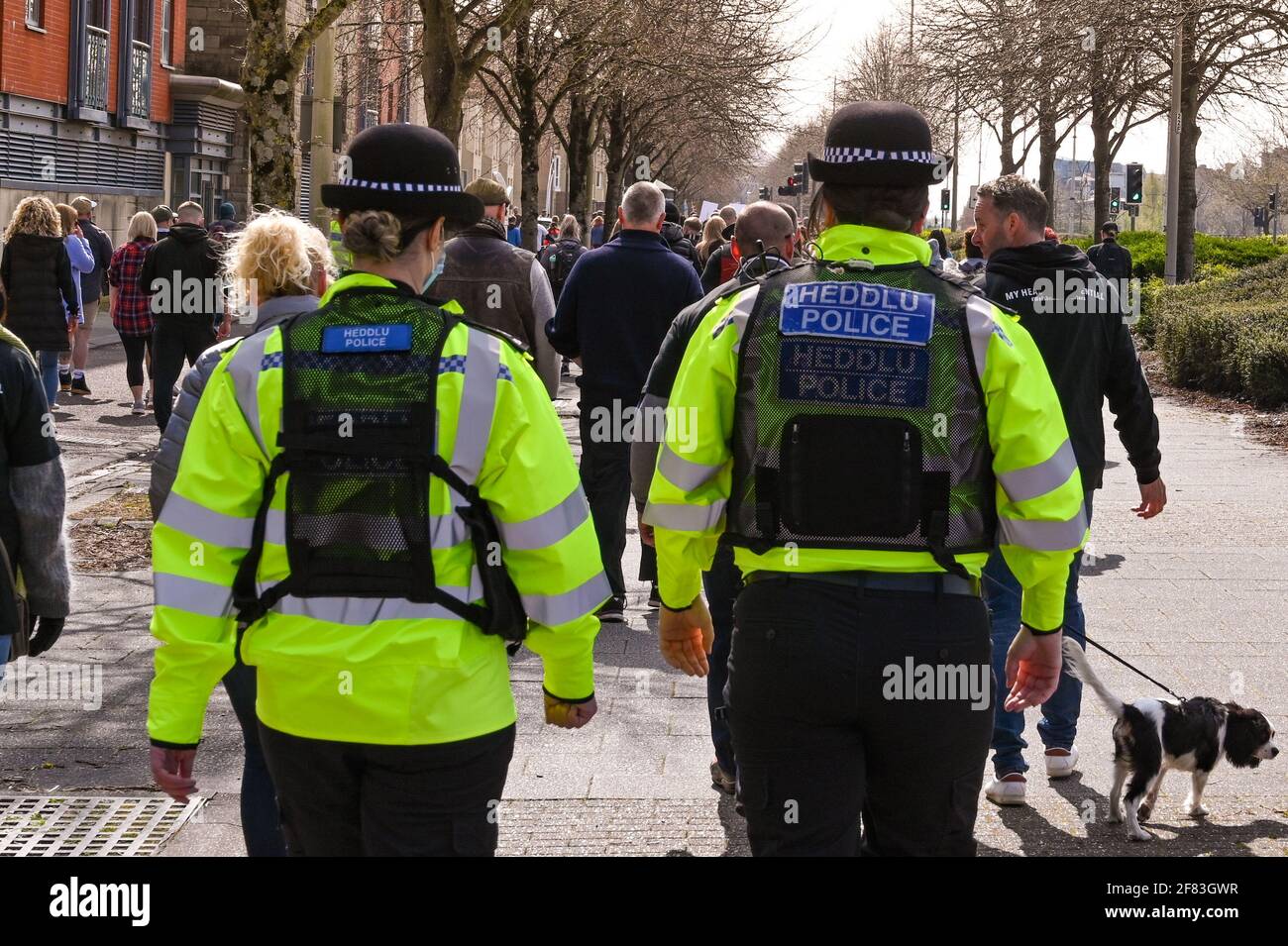 Cardiff, Wales - April 2021: Two police officers escorting a crowd of people at a public march in Cardiff Stock Photo