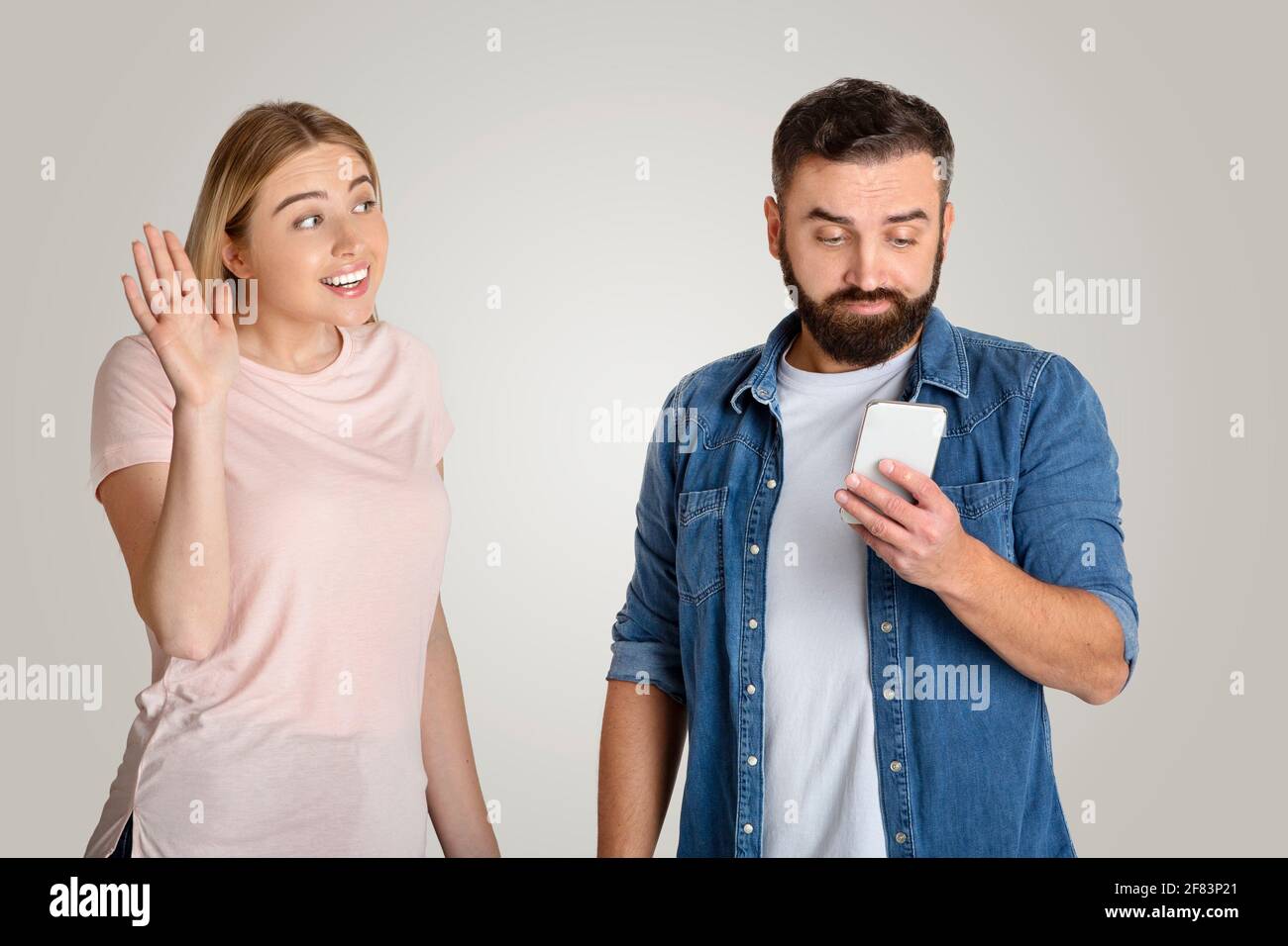 Cheating, indifference and problems in family. Young woman waves and draws attention of busy guy Stock Photo