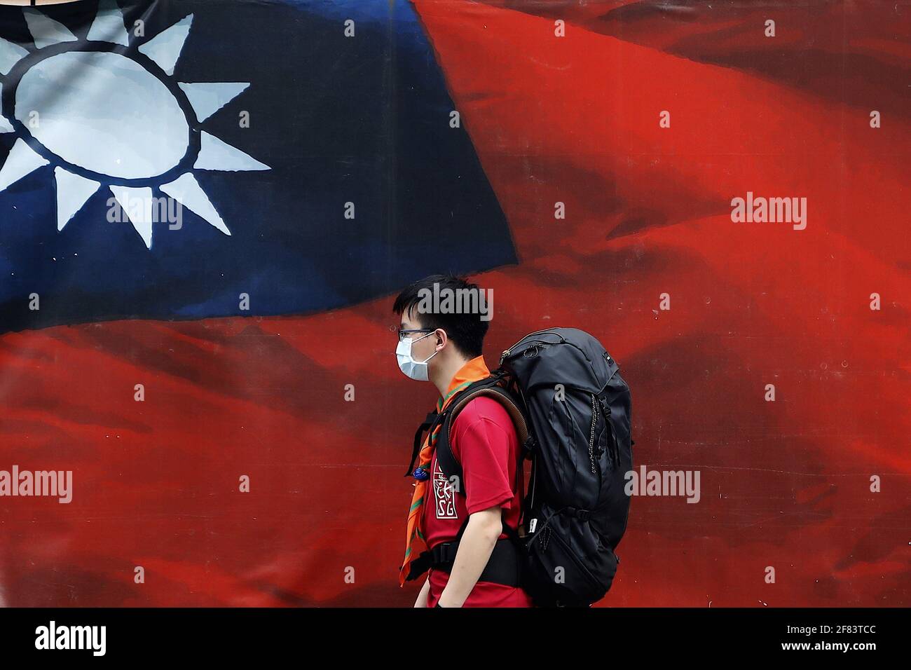 Taipei, Taiwan. 11th Apr, 2021. Taiwanese people wearing a face mask walk past a huge banner with a Taiwan national flag amid increased tensions with China. With Beijing sending more jet fighters cruising around the island, Taiwan foreign minister Joseph Wu has said Taiwan will defend itself to the 'very last day'' whilst it has been fostering relationship with the United States on military, economy, technology and medical services. Credit: Daniel Ceng Shou-Yi/ZUMA Wire/Alamy Live News Stock Photo