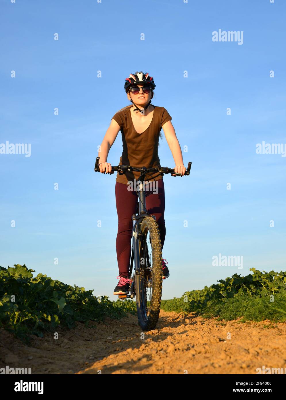 Girl riding a bike on a dirt road. Stock Photo