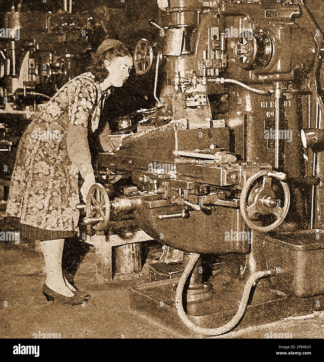 WW2 - Women at work in Britain in 1941 - A press photo of the time showing a female mechanic operating a machine gun part  manufacturing  machine. Stock Photo